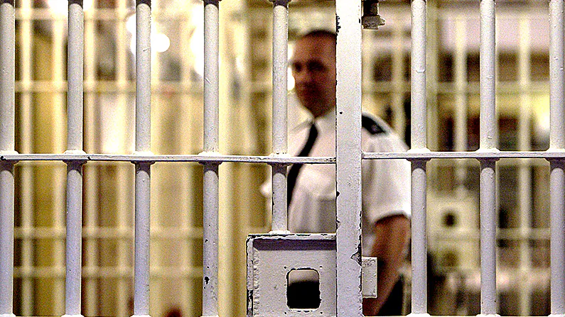 A prison guard at HMP Pentonville stands behind a locked gate in London on May 19, 2003. (Ian Waldie/Getty Images)