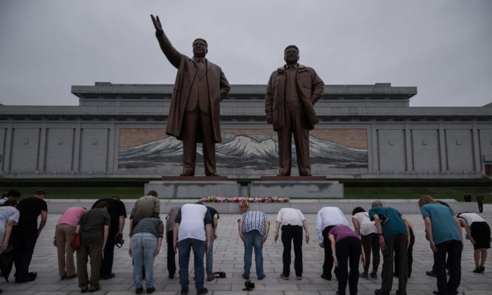 A group of tourists—on command from their guide to bow deeply—bow before statues of late North Korean leaders Kim Il-Sung (L) and Kim Jong-Il (R), on Mansu Hill in Pyongyang on July 23, 2017. North Korean authorities have increased the amount of 24-hour guarding at sites like this to prevent vandalism. (ED JONES/AFP/Getty Images)