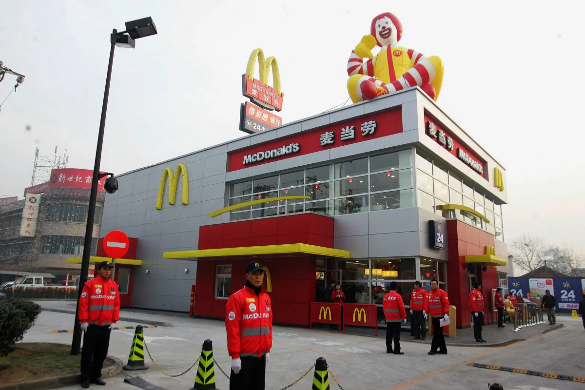 Chinese staff wait for the first customers at the opening of a McDonald's drive-thru outlet built next to a gas station in Beijing on Jan. 19, 2007. McDonald’s, after announcing that it would change its name in China, drew ridicules on Chinese social media. (STR/AFP/Getty Images)