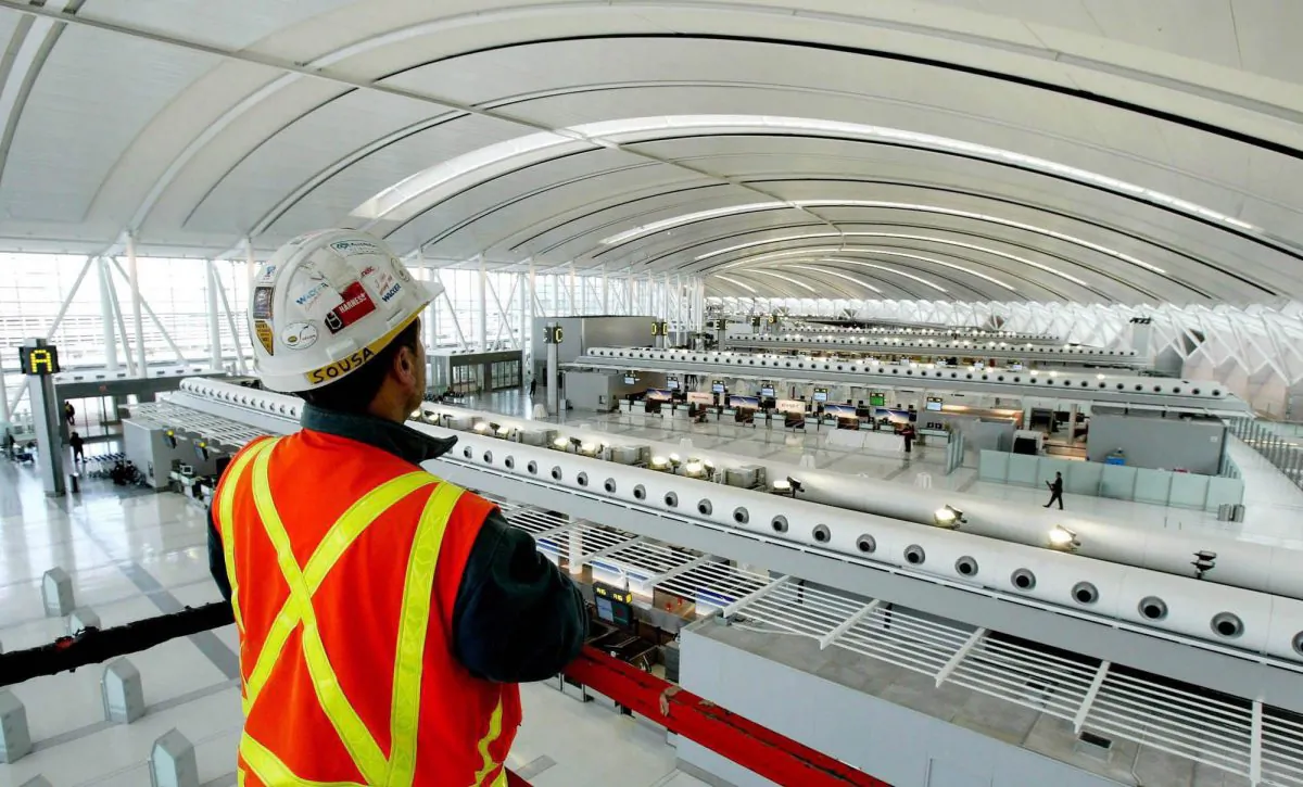 An Aecon employee looks at Toronto Pearson International Airport's check-in area. A Chinese state-owned enterprise is looking to acquire the Canadian construction firm, necessitating a government review. (Canadian Press/AP, Tobin Grimshaw)