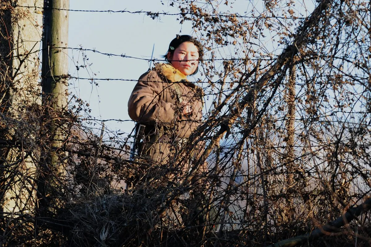 An armed North Korean female soldier keeps watch behind a barbed wire fence on the banks of the Yalu River near Dandong in northeast China's Liaoning province on Nov. 25, 2010. (FREDERIC J. BROWN/AFP/Getty Images)