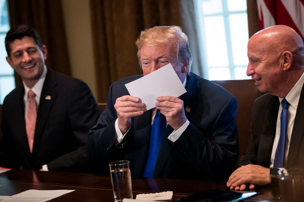 Flanked by Speaker of the House Paul Ryan and House Ways and Means Committee chairman Rep. Kevin Brady (R-TX), President Donald Trump kisses an example of what a new tax form may look like as he speaks about tax reform legislation in the Cabinet Room at the White House in Washington, DC, on Nov. 2, 2017. (Drew Angerer/Getty Images)