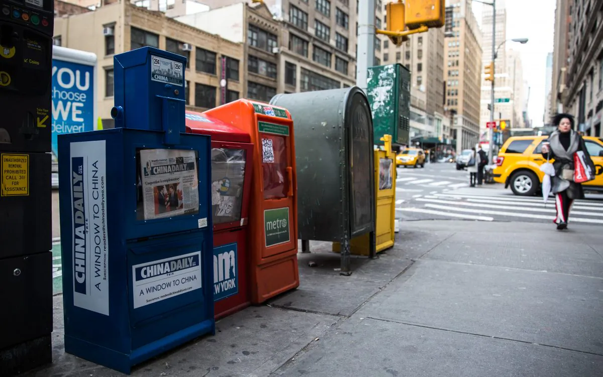 A paid China Daily newspaper box next to free daily papers in Midtown Manhattan, New York, on Dec. 6, 2017. (Benjamin Chasteen/The Epoch Times)