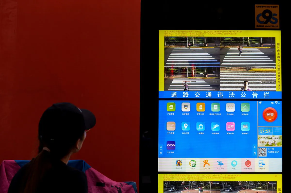 A woman looks at a screen projecting pictures of people crossing the roads or offending traffic rules in Shanghai, China, on August 9, 2017. (Chandan Khanna/AFP/Getty Images)
