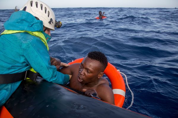 A migrant is helped boarding a boat