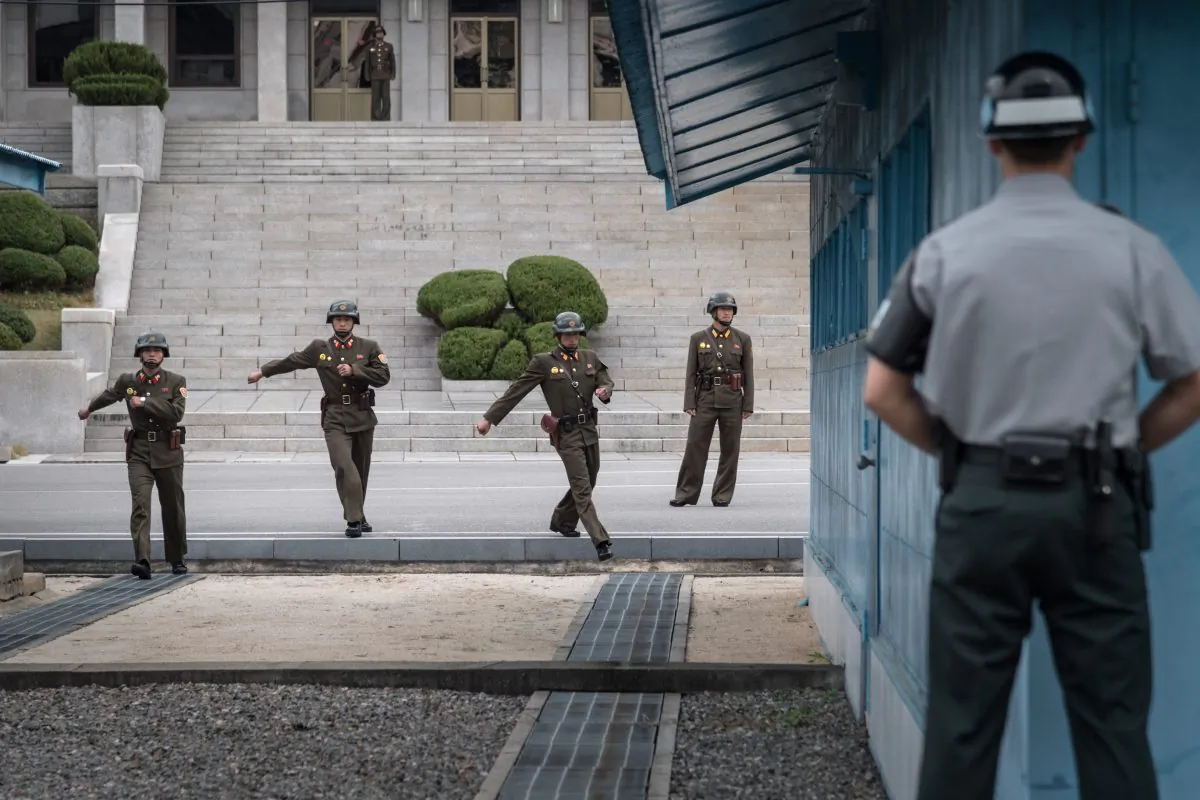 A South Korean soldier (R) stands before North Korean soldiers walking towards the military demarcation line separating North and South Korea at the truce village of Panmunjom on Oct. 12, 2017. A North Korean soldier at Panmunjom defected to the South on Nov. 13, 2017, and was shot and wounded by the North Korean military while crossing the border. (AFP/Getty Images)