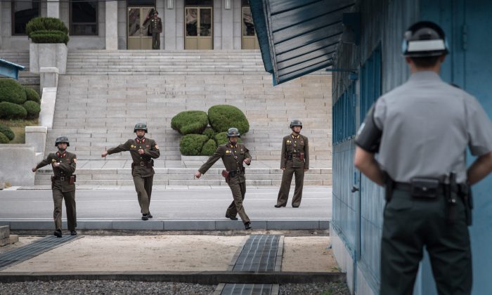 A South Korean soldier (R) stands before North Korean soldiers walking towards the military demarcation line separating North and South Korea at the truce village of Panmunjom on Oct. 12, 2017. A North Korean soldier at Panmunjom defected to the South on Nov. 13, 2017, and was shot and wounded by the North Korean military while crossing the border. (AFP/Getty Images)