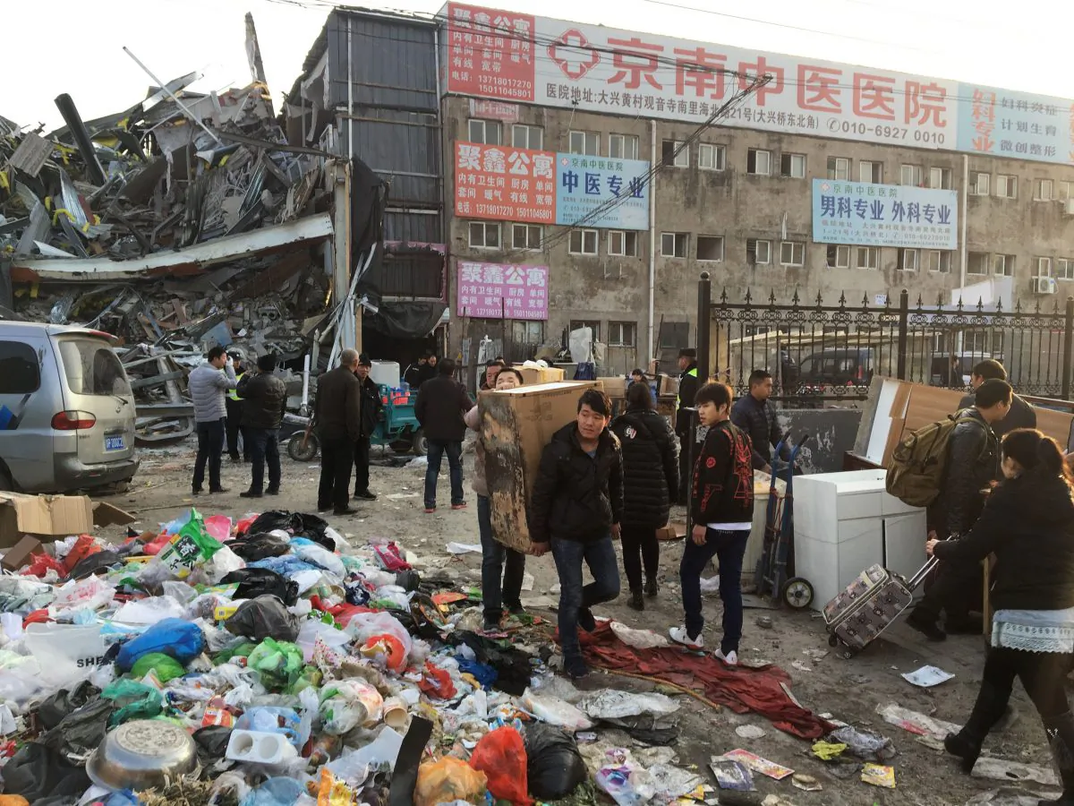 Residents carry their belongings as they evacuate the site of a fatal housing block fire that killed 19 people and injured eight in Beijing on November 19, 2017. (Ryan Mcmorrow/AFP/Getty Images)