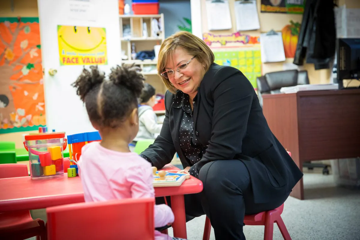 Carla Tellez, founder of Our Children First, a therapeutic learning center for children, is with a child at the center in the Bronx borough of New York on Nov. 22, 2017. (Benjamin Chasteen/The Epoch Times)