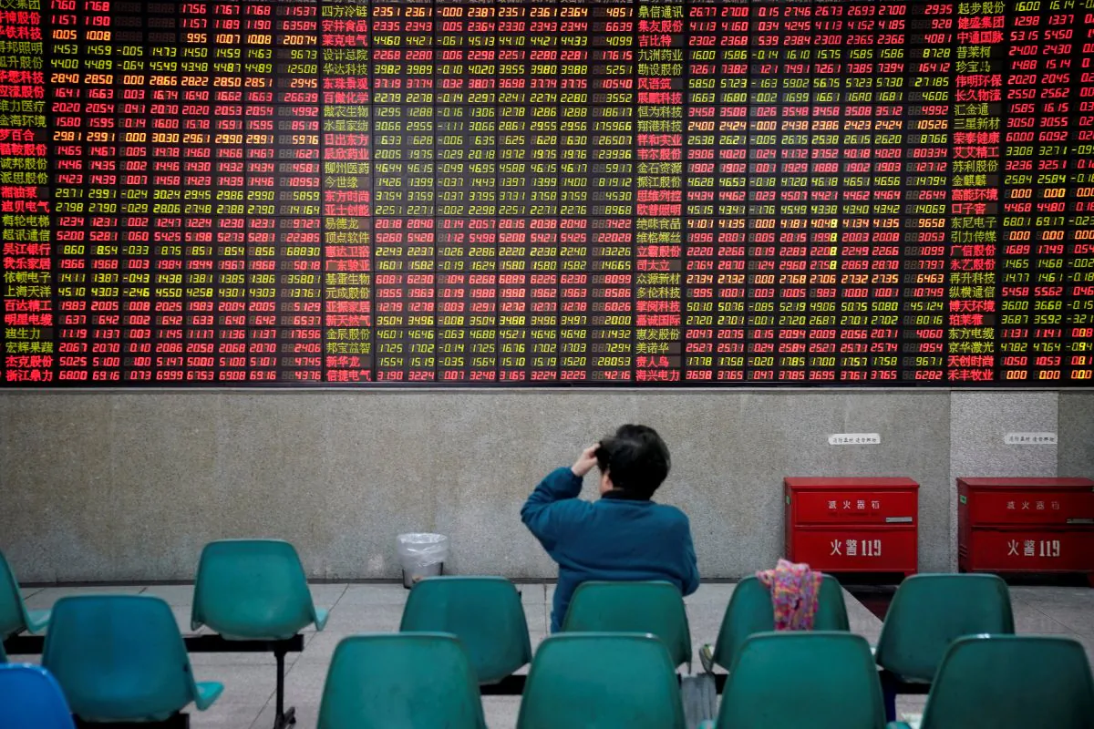An investor watches board showing stock information at a brokerage house in Shanghai on Nov. 24, 2017. (REUTERS/Aly Song
