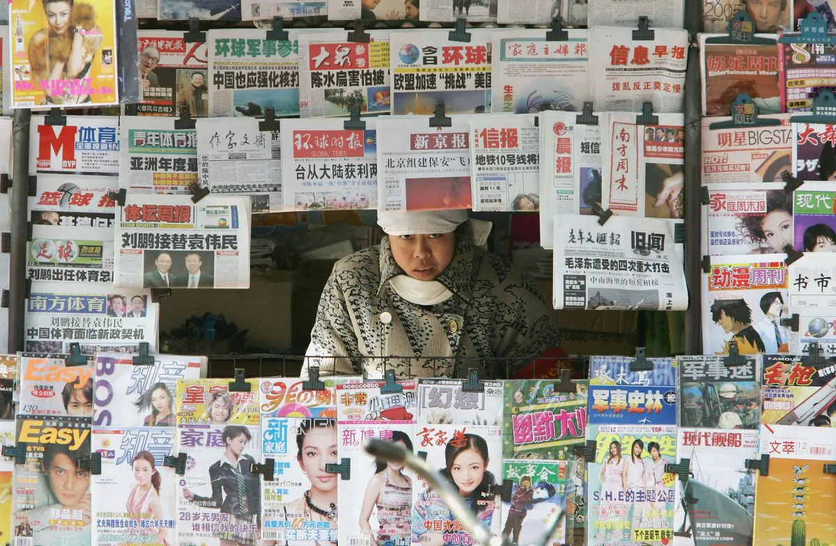 A newspaper vendor peers from her stall in Beijing, China, on Dec. 10, 2004. (Guang Niu/Getty Images)