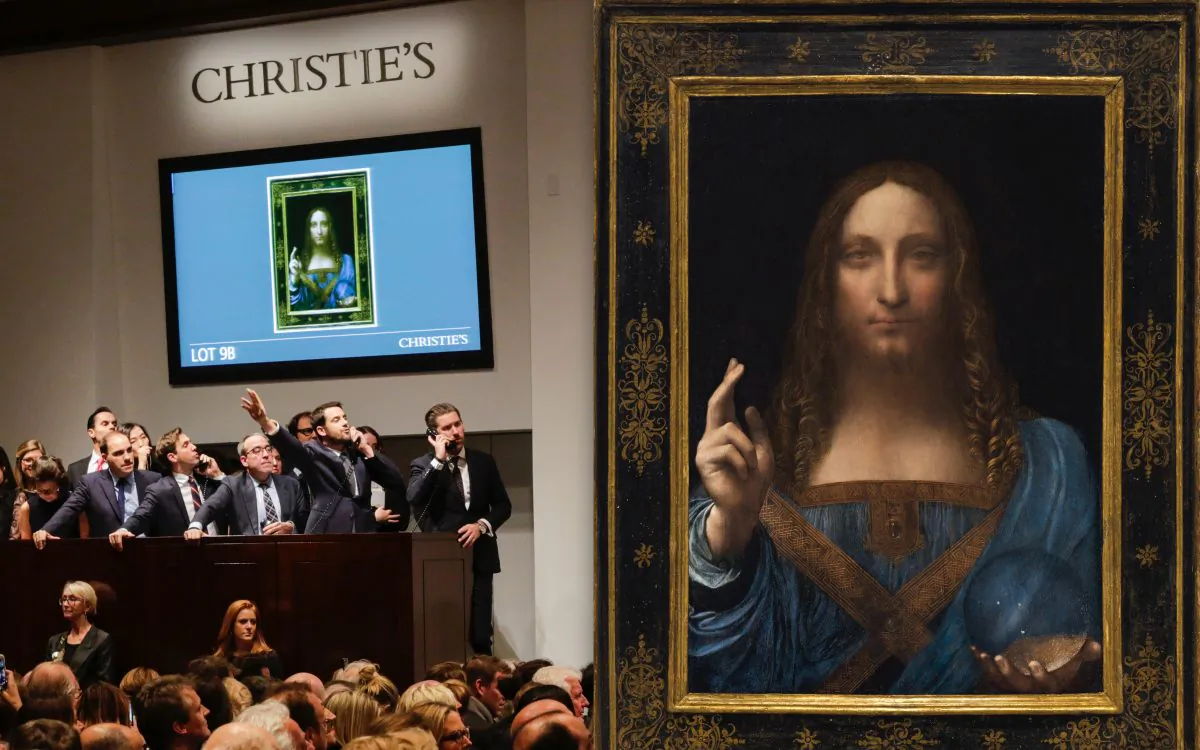 (L) Agents speak on their phones with their clients while bidding on at the auction of Leonardo da Vinci's "Salvator Mundi" during the Post-War and Contemporary Art evening sale at Christie's on Nov. 15, 2017 in New York City. (Eduardo Munoz Alvarez/Getty Images) (R) “Salvator Mundi,” circa 1500, by Leonardo da Vinci (1452–1519). Oil on walnut wood panel, 25 7/8 inches by 18 inches, private collection. (Christie’s)