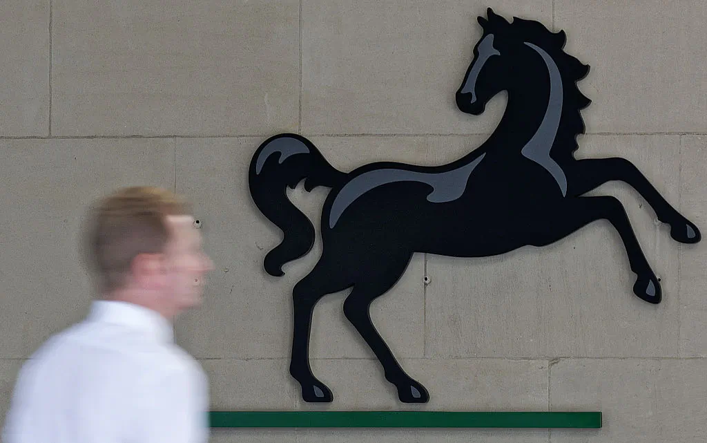A man passes a Lloyds logo outside the entrance to an office of Lloyds Banking Group in the City of London on July 28, 2016. (Justin Tallis/AFP/Getty Images)