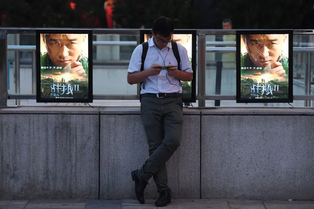 A man stands in front of movie posters for 'Wolf Warriors 2' in Beijing on Aug. 7, 2017. (Greg Baker/AFP/Getty Images)