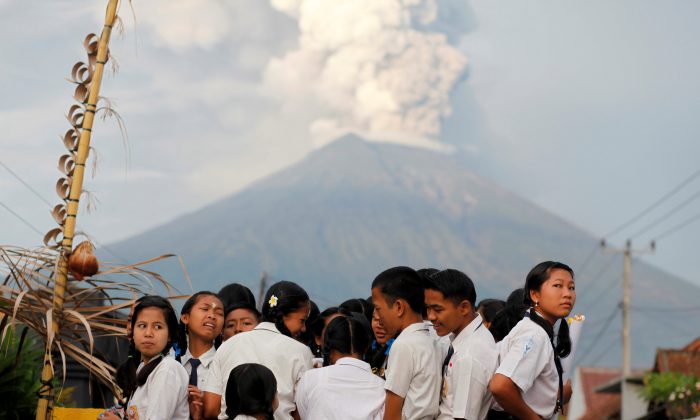 School children ride on the back of a truck on their way to school as Mount Agung volcano erupts in the background near Amed, Karangasem Regency, Bali, Indonesia. (Reuters/Nyimas Laula)