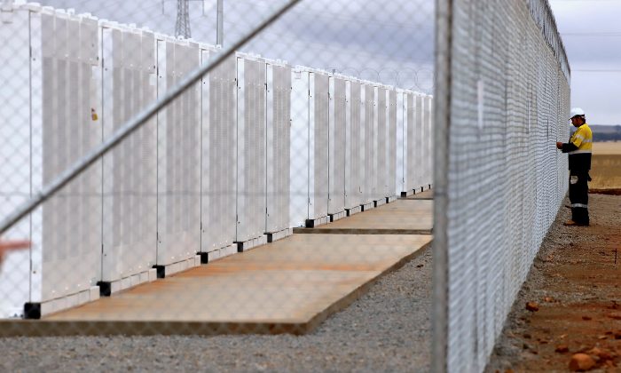 2017 年 12 月 1 日，在澳大利亚南澳大利亚州詹姆斯敦镇附近的正式发布期间，一名工人正在检查 Hornsdale Power Reserve 所在院落的围栏，该院拥有特斯拉制造的世界上最大的锂离子电池。（David Gray/路透社）