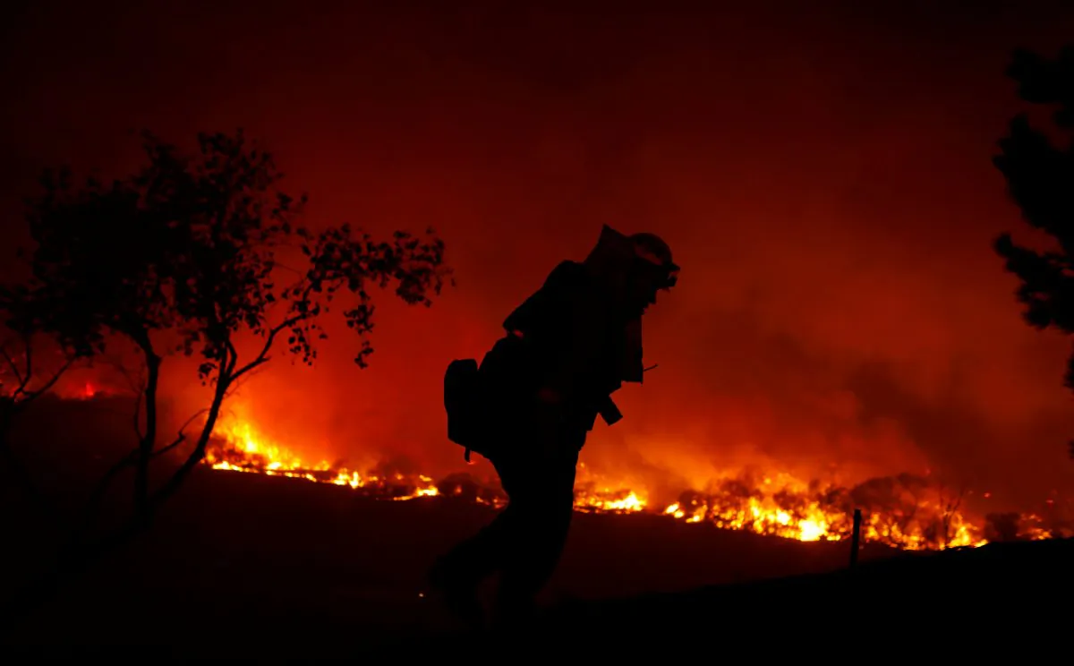 A firefighter is working on extinguishing the Lilac Fire, a fast moving wildfire in Bonsall, California, U.S., December 7, 2017.      (Reuters/Mike Blake)
