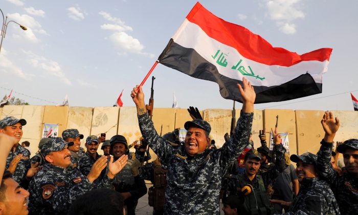 FILE PHOTO: A member of Iraqi Federal Police waves an Iraqi flag as they celebrate victory of military operations against the ISIS terrorists in West Mosul, Iraq July 2, 2017. (Reuters/Erik De Castro/File Photo)