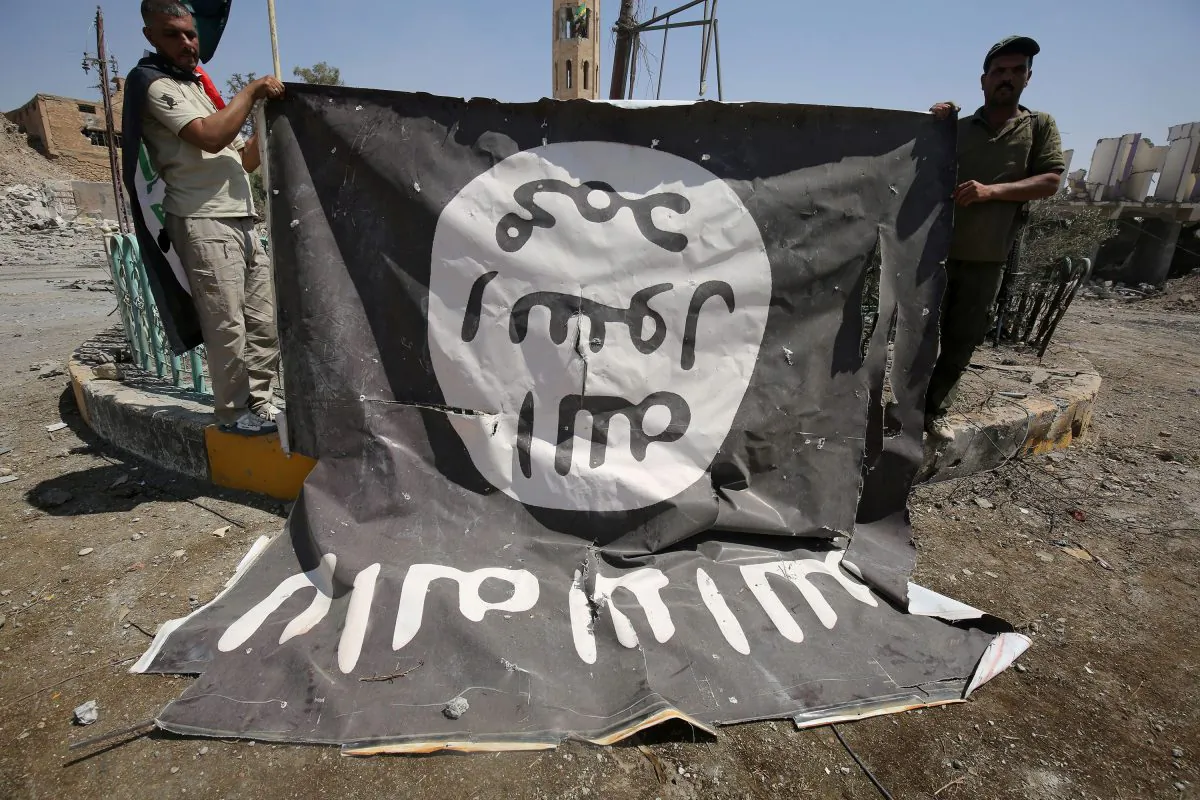 Fighters from the Hashed al-Shaabi, backing the Iraqi forces, pose for a photograph with a flag of the ISIS terrorist group in Tal Afar's Qalea central district during an operation to retake the city from the jihadists on Aug 27, 2017. (Ahmad Al-Rubaye/AFP/Getty Images)