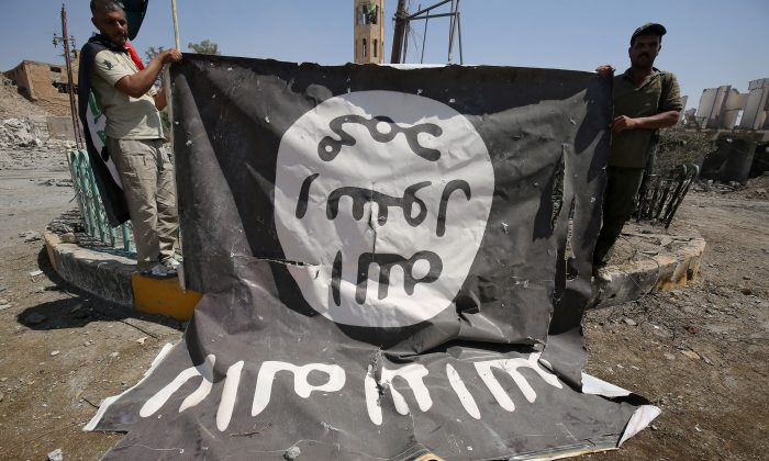 Fighters from the Hashed al-Shaabi, backing the Iraqi forces, pose for a photograph with a flag of the ISIS terrorist group in Tal Afar's Qalea central district during an operation to retake the city from the jihadists on Aug 27, 2017. (Ahmad Al-Rubaye/AFP/Getty Images)