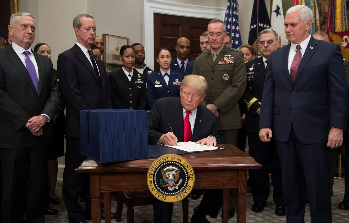 President Donald Trump, surrounded by military officials and members of Congress, including Vice President Mike Pence (R) and Secretary of Defense Jim Mattis (L), signs H.R. 2810, National Defense Authorization Act for Fiscal Year 2018, in the Roosevelt Room at the White House in Washington, DC, Dec. 12, 2017. (SAUL LOEB/AFP/Getty Images)