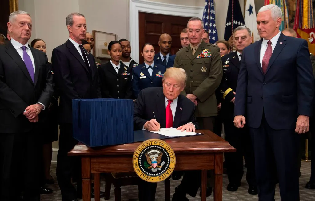 US President Donald Trump, surrounded by military officials and members of Congress, including Vice President Mike Pence (R) and Secretary of Defense Jim Mattis (L), signs H.R. 2810, National Defense Authorization Act for Fiscal Year 2018, during a signing ceremony in the Roosevelt Room at the White House in Washington, DC, Dec. 12, 2017. (SAUL LOEB/AFP/Getty Images)