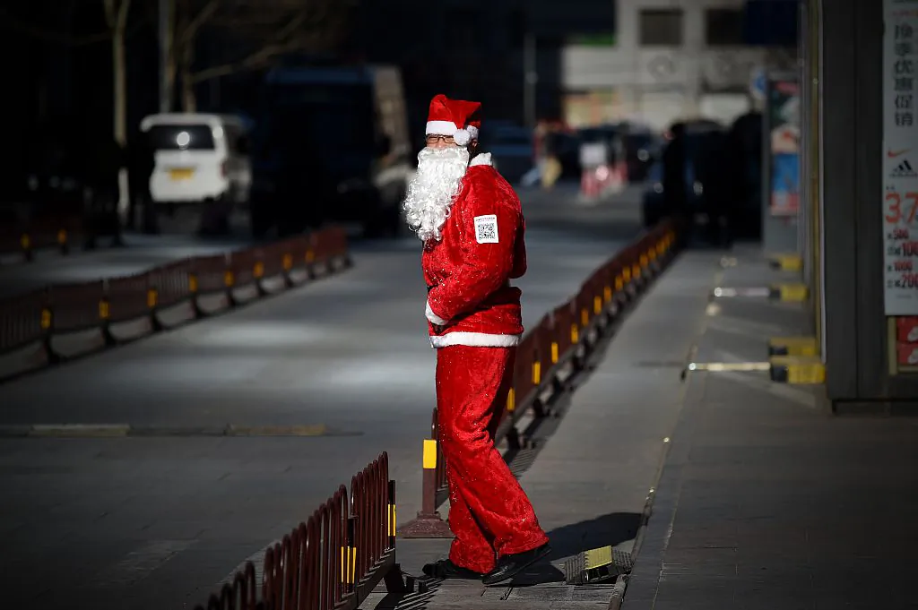 A salesman dressed as Santa Claus waits for customers at the entrance of a shop in Beijing on December 25, 2014. (Wang Zhao/AFP/Getty Images)