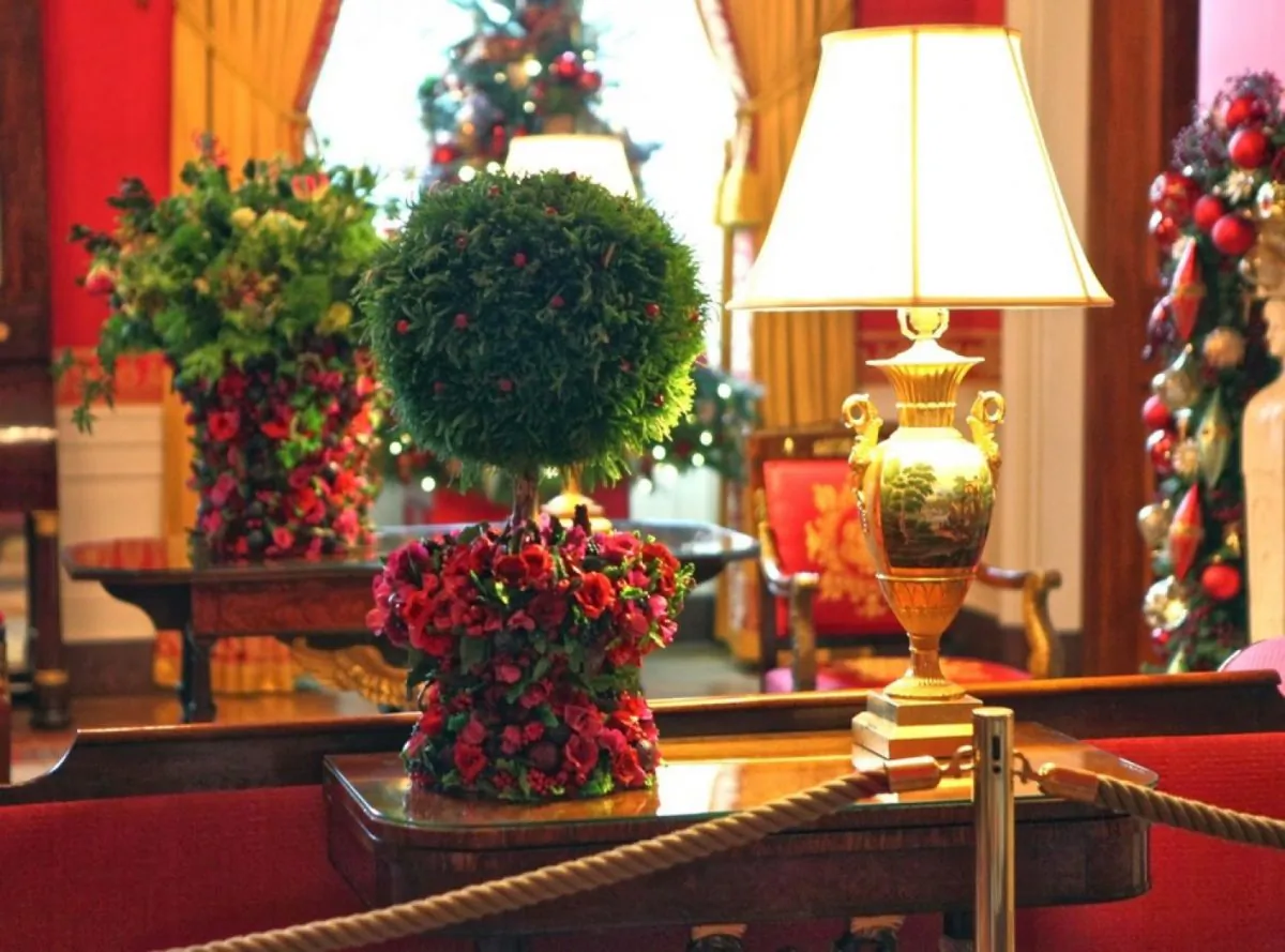 Two hand-made sugar flower vases: one featuring a princess pine topiary and the other a lush display of green flowers and ferns with red berries to add bold colors and texture to the Red Room, as designed by Laura Dowling during her tenure as chief floral designer for the White House. (Stichting Kunstboek BVBA)