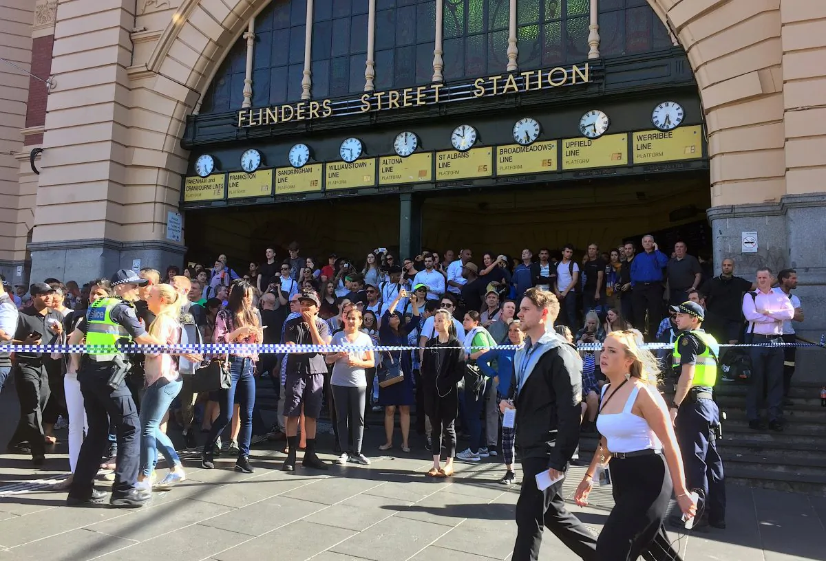 Members of the public stand behind police tape after Australian police said they have arrested the driver of a vehicle that ploughed into pedestrians at a crowded intersection near the Flinders Street train station in central Melbourne, Australia Dec. 21, 2017.  (Reuters/Melanie Burton)