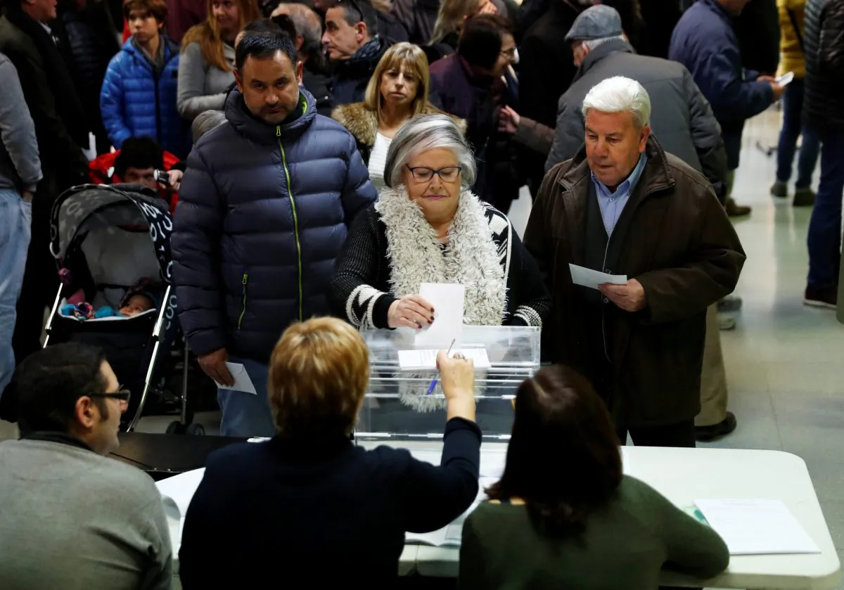 A woman casts her ballot as others wait to vote in Catalonia's regional elections at a polling station in Vic, Spain December 21, 2017. (Reuters/Juan Medina)