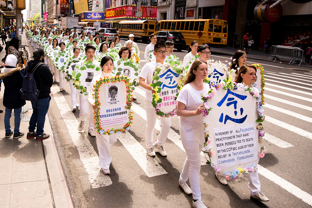 Falun Gong practitioners hold wreaths with photos of people who were killed inside China for their beliefs, at a parade along 42nd Street in New York City on May 12, 2017. (Samira Bouaou/The Epoch Times)