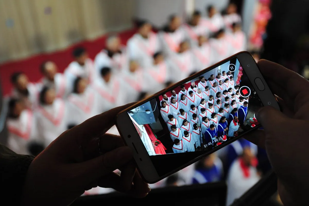 This photo taken on December 24, 2017 shows a participant taking a video as a choir sings hymns during a Christmas Eve mass at a church in Fuyang in China's eastern Anhui province. Reports from across China indicate that Christmas celebrations this year by Chinese Christians have been widely suppressed by the authority. (AFP/Getty Images)