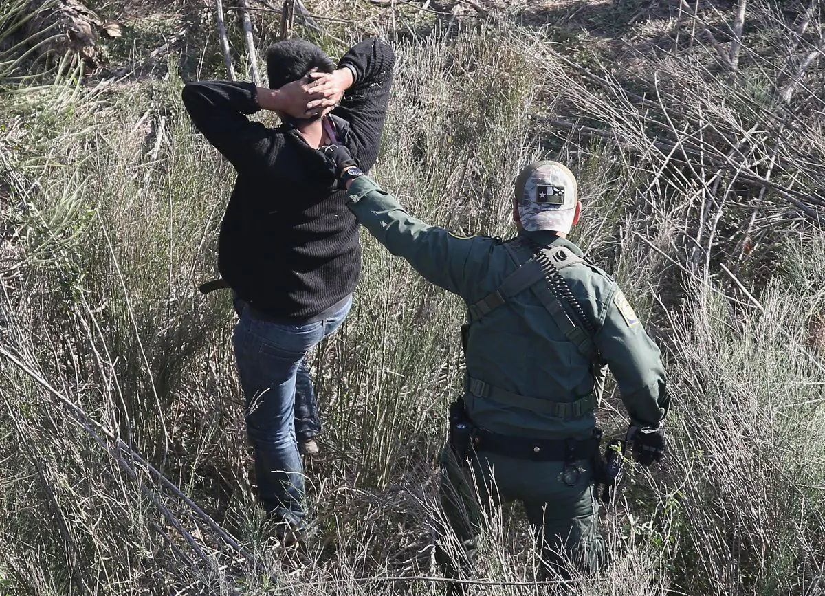 A Border Patrol agent leads an illegal alien out from the brush after capturing him near the U.S.–Mexico border at La Grulla, Texas, on Dec. 10, 2015. (John Moore/Getty Images)