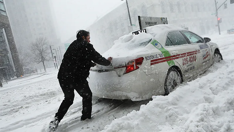 A man pushes a taxi car in the streets of Boston as snow falls from a massive winter storm on Jan. 4, 2018. (Spencer Platt/Getty Images)