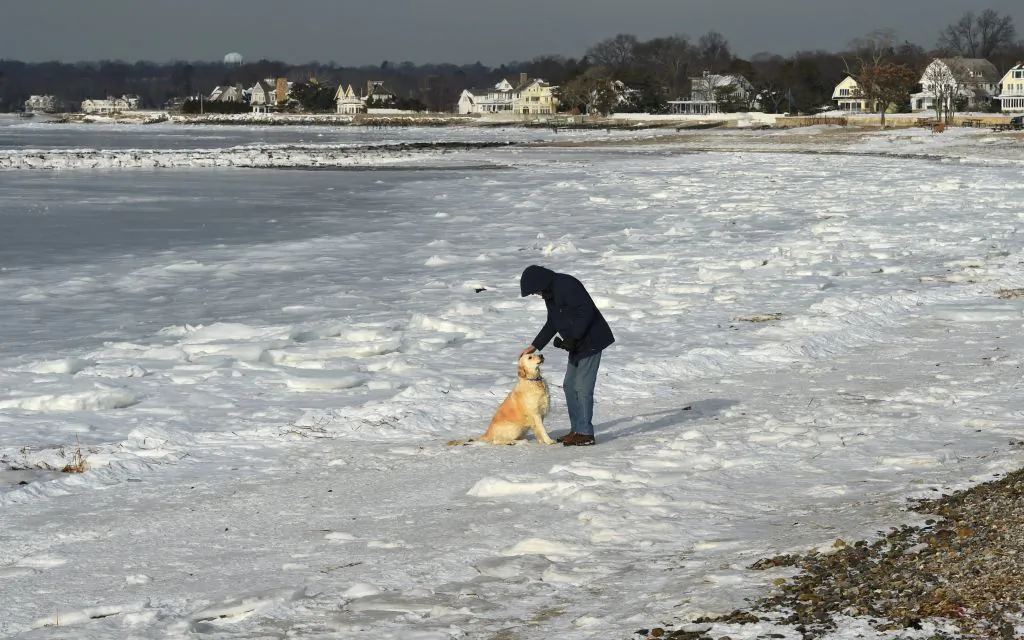 Dick Healy of Wesport, Conn., walks his dog along the frozen Long Island Sound at Compo Beach in Westport, Conn January 8, 2018. The northeast is still facing record low temperatures but warmer weather is on the way. (Timothy A. Clary/AFP/Getty Images)