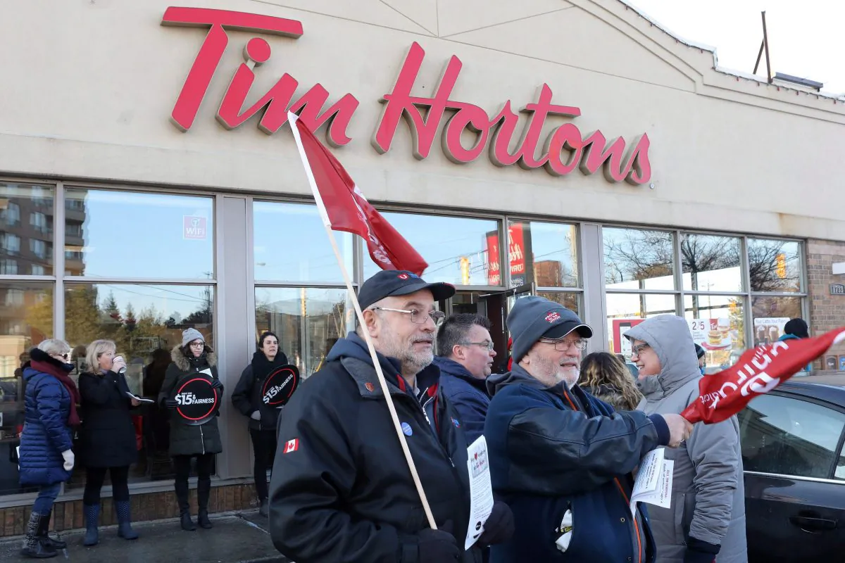 Ontario Federation of Labour members protest outside a Tim Hortons franchise in Toronto on Jan. 10. Labour organizations across Ontario held rallies on Jan. 10 to protest the cuts in benefits some Tim Hortons franchises have taken in response to an increase in the province’s minimum wage. (The Canadian Press/Chris Young)