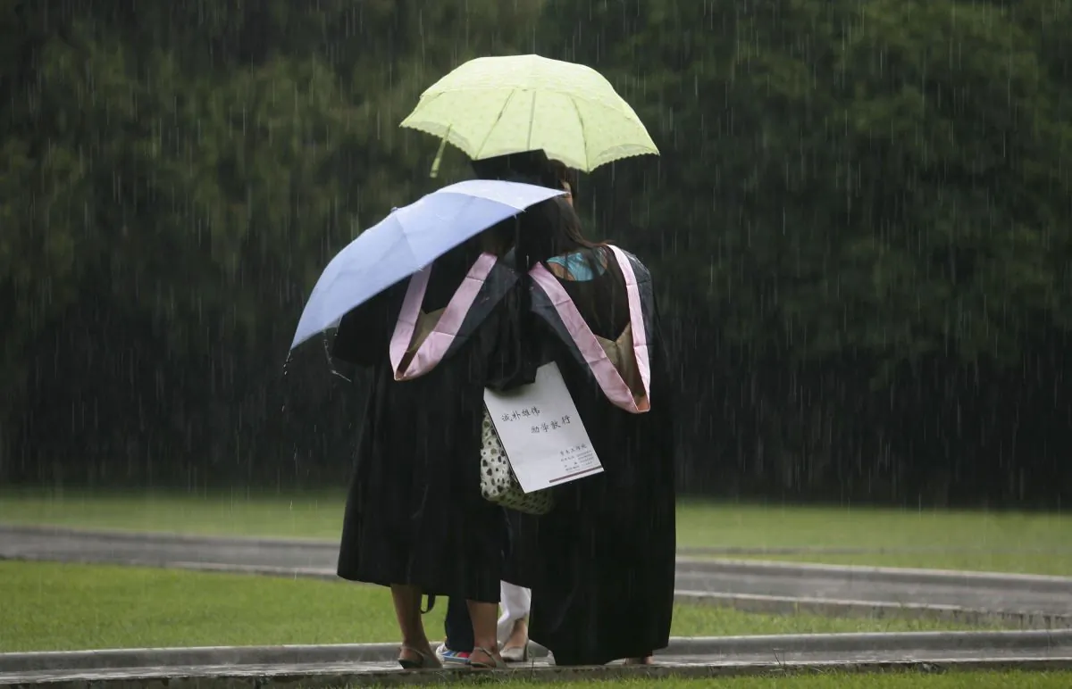 Graduates pose for pictures in the rain during a graduation ceremony in Nanjing City of Jiangsu Province, on June 20, 2006. (China Photos/Getty Images)