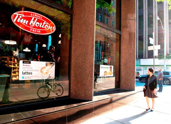 A woman walks past a Tim Hortons coffee shop in Toronto. (The Canadian Press/Doug Ives)