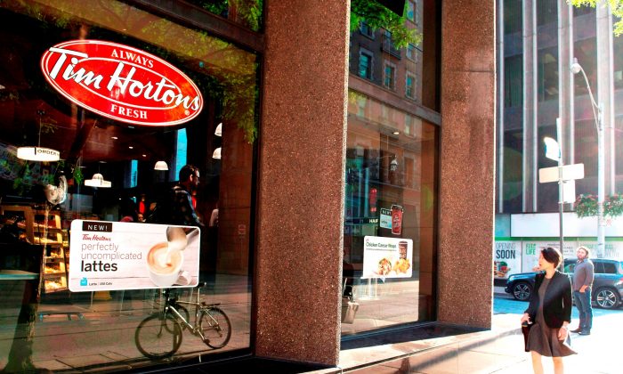 A woman walks past a Tim Hortons coffee shop in Toronto. (The Canadian Press/Doug Ives)