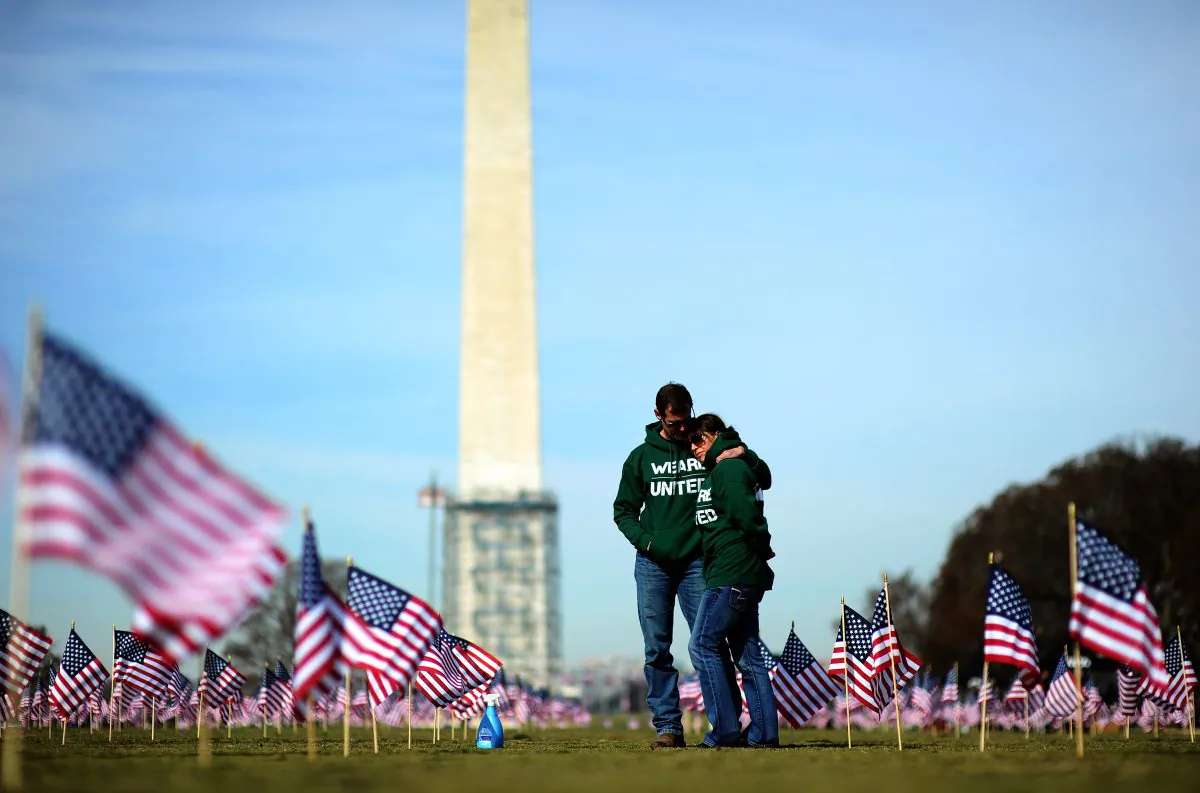 Iraq war veteran couple Colleen Ryan and Jeff Hensley of the U.S. Navy comfort each other as they help set up 1,892 American flags on the National Mall in Washington, DC, on March 27, 2014. The Iraq and Afghanistan veterans installed the flags to represent the 1,892 veterans and service members who committed suicide this year as part of the "We've Got Your Back: IAVA's Campaign to Combat Suicide." (JEWEL SAMAD/AFP/Getty Images)
