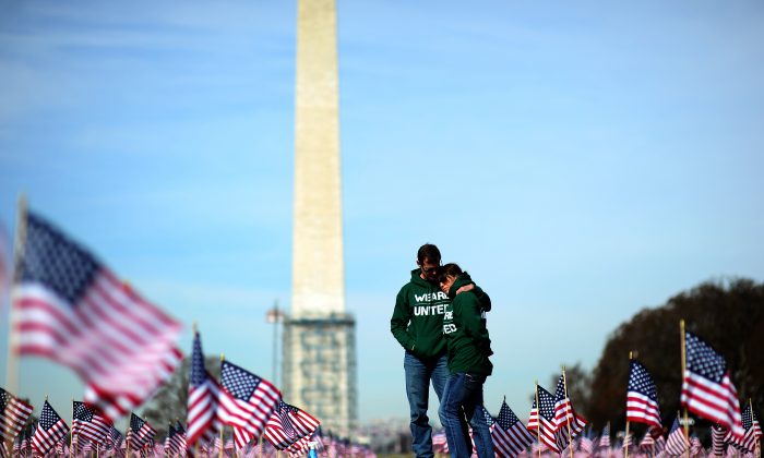 Iraq war veteran couple Colleen Ryan and Jeff Hensley of the U.S. Navy comfort each other as they help set up 1,892 American flags on the National Mall in Washington, DC, on March 27, 2014. The Iraq and Afghanistan veterans installed the flags to represent the 1,892 veterans and service members who committed suicide this year as part of the "We've Got Your Back: IAVA's Campaign to Combat Suicide."   (JEWEL SAMAD/AFP/Getty Images)