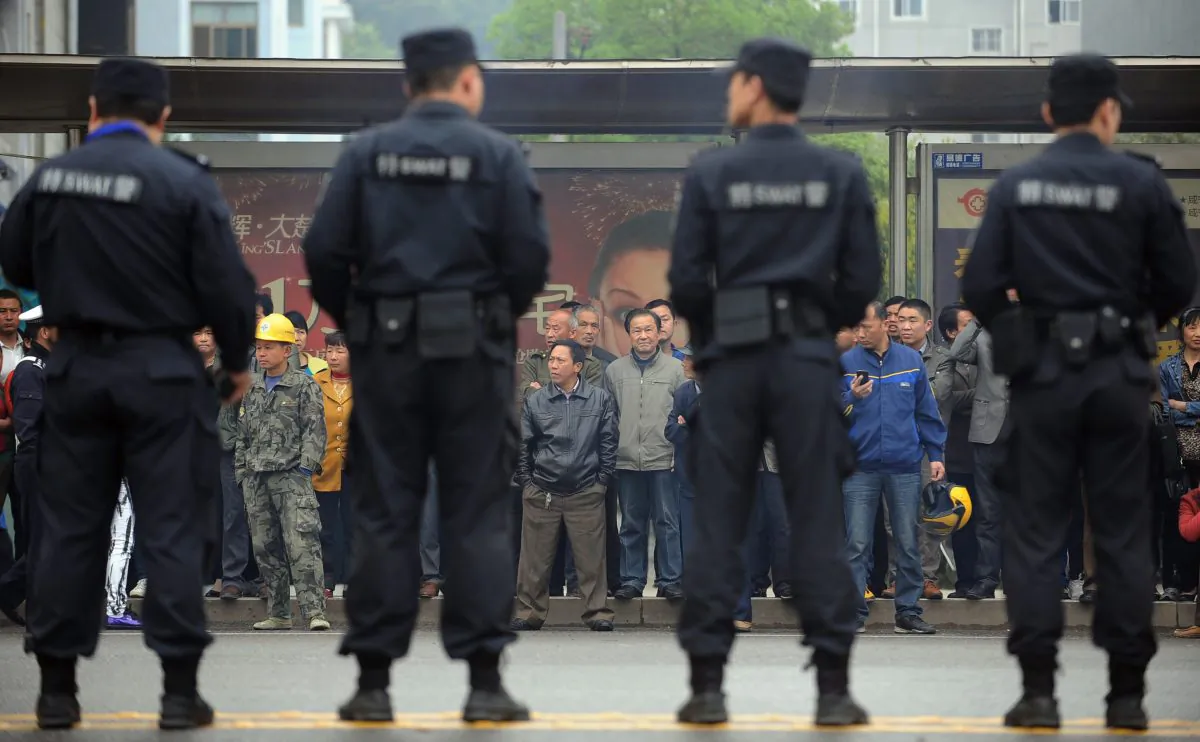 Citizens watch as police stand guard outside the Xianning Intermediate People's Court in Xianning City, central China's Hubei Province, on March 31, 2014. (STR/AFP/Getty Images)