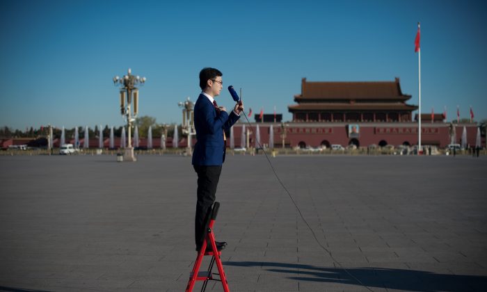 A television journalist stands on a ladder as he reports in Tiananmen Square in Beijing on March 13, 2017. (Nicolas Asfouri/AFP/Getty Images)