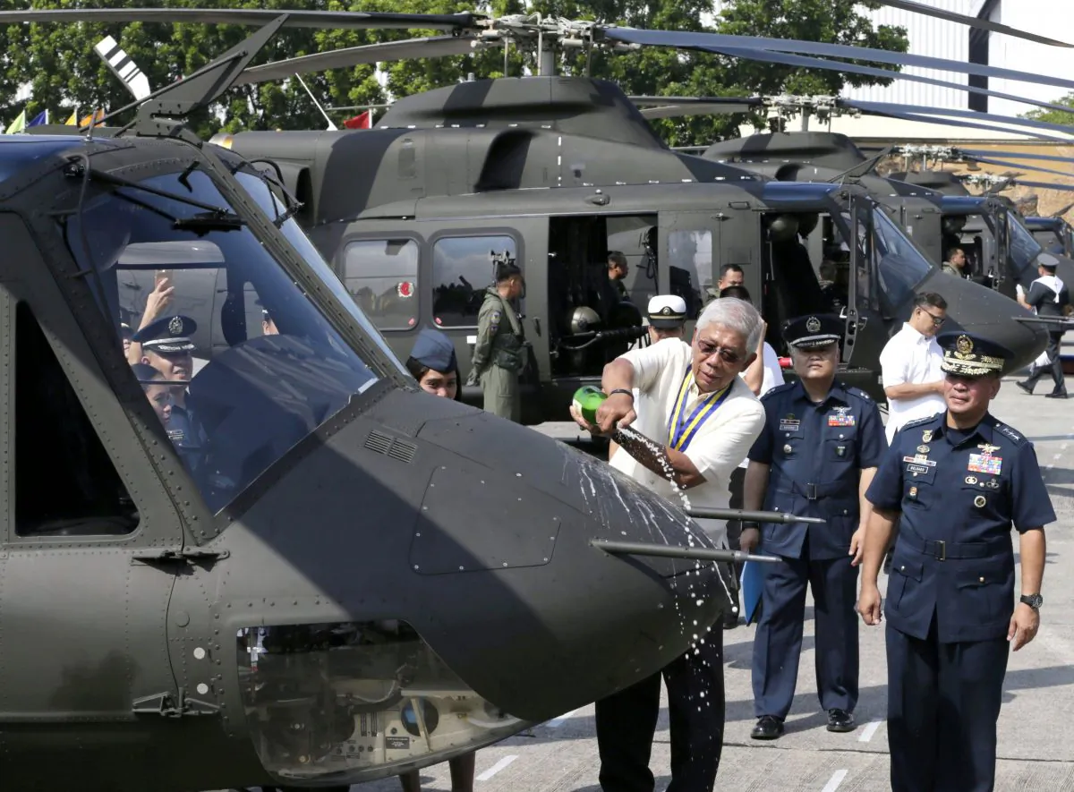 Philippine National Defense Chief Voltaire Gazmin pours champagne on one of eight helicopters procured by the Philippine Air Force from Bell Helicopter Textron Canada during a ceremony at Villamor Air Base south of Manila on Aug. 17, 2015. (AP Photo/Bullit Marquez)