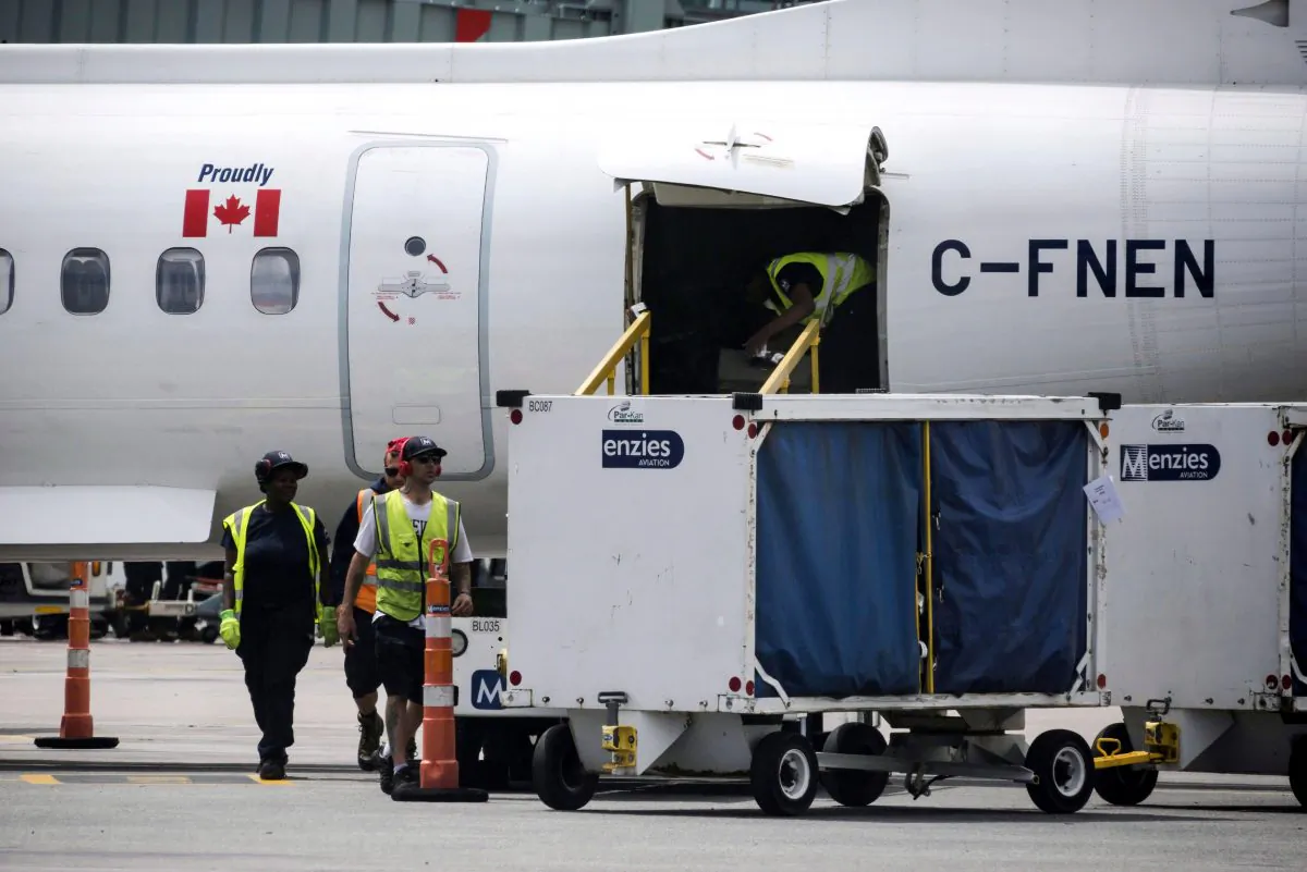 Baggage handlers remove luggage from a WestJet aircraft in a file photo (The Canadian Press/Christopher Katsarov)