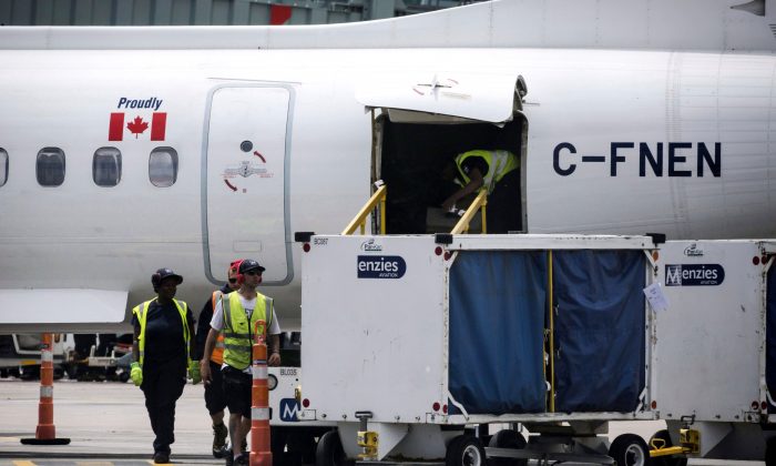 Baggage handlers remove luggage from a WestJet aircraft in a file photo (The Canadian Press/Christopher Katsarov)