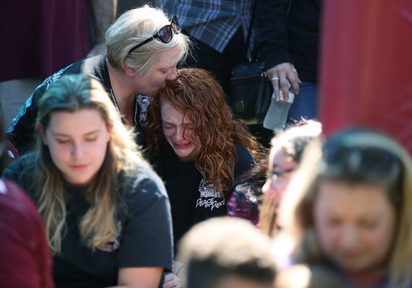 A student from the school where a mass shooting took place is comforted by her mother