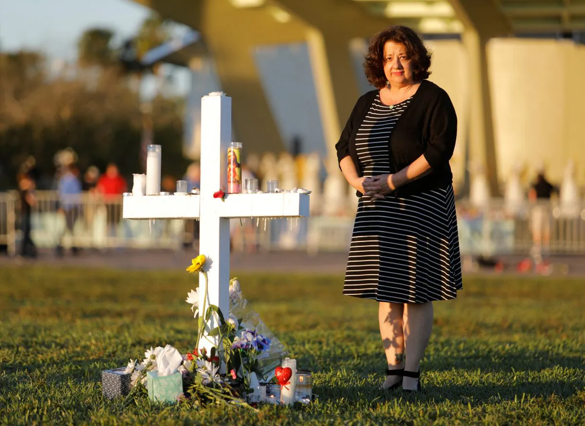 Diana Haneski, a librarian at Marjory Stoneman Douglas High School, poses for a portrait near one of the crosses erected for the victims of the school shooting in Parkland, Florida, U.S. February 16, 2018. (Reuters/Jonathan Drake)