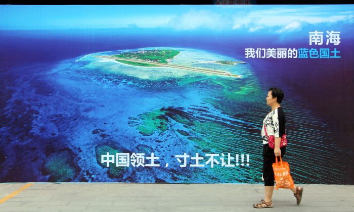 A woman walking past a poster of the South China Sea, with the slogan at the bottom 