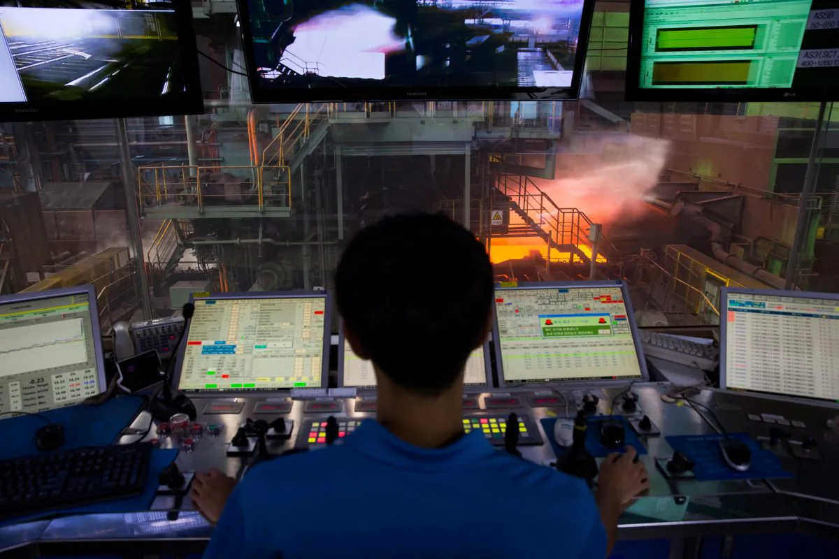 Steel plates being rolled with an engineer looking on. (Seong Joon Cho/Worldsteel via Getty Images)